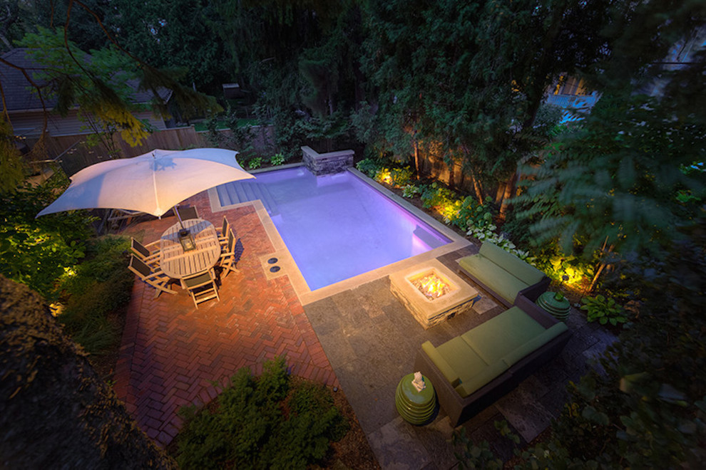 This is an example of a mid-sized transitional backyard l-shaped natural pool in Toronto with a hot tub and brick pavers.