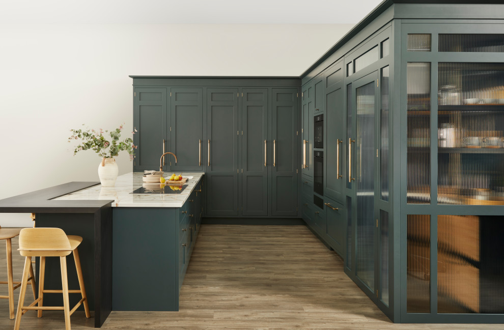 This is an example of a large classic u-shaped open plan kitchen in Berkshire with a single-bowl sink, shaker cabinets, green cabinets, marble worktops, integrated appliances, laminate floors, an island, brown floors, white worktops and a feature wall.