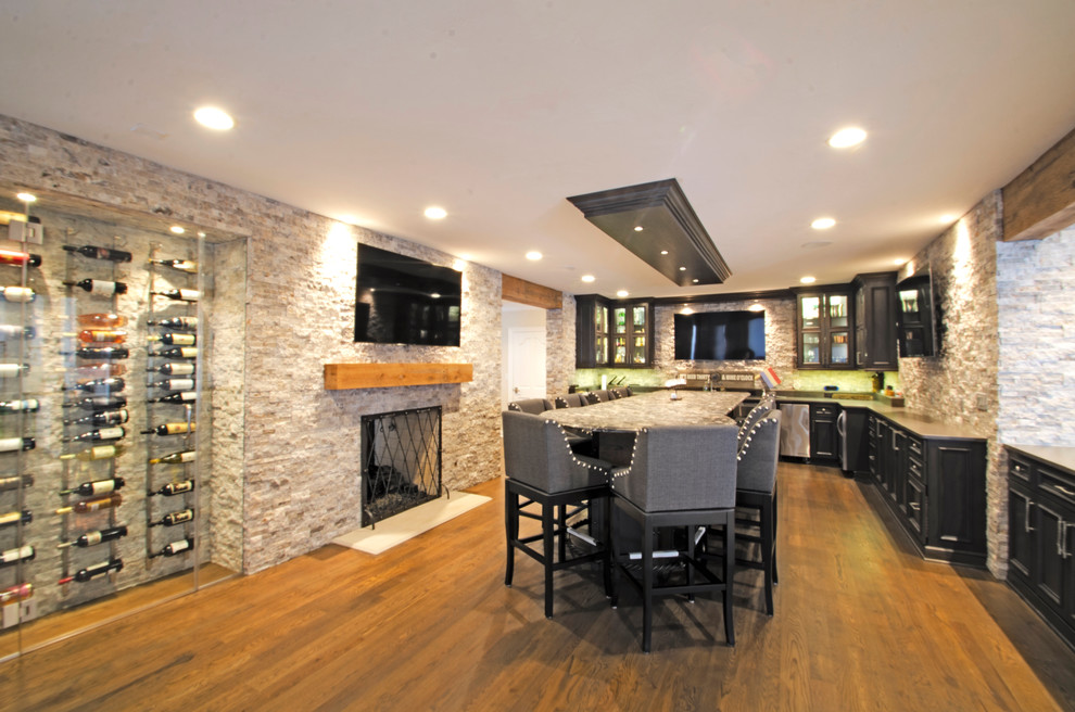 This is an example of a large transitional fully buried basement in Milwaukee with dark hardwood floors, a standard fireplace, a stone fireplace surround and brown floor.