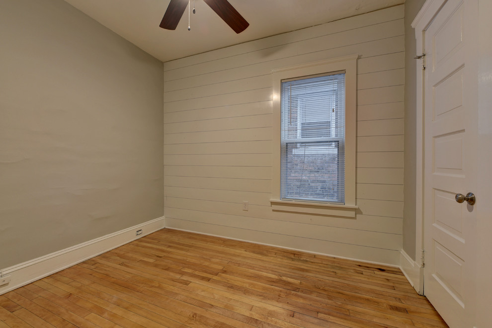 This is an example of a mid-sized transitional guest bedroom in Cleveland with grey walls, medium hardwood floors, no fireplace and brown floor.