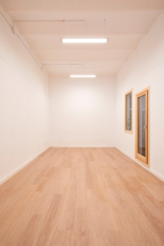 This is an example of a small scandinavian home yoga studio in Barcelona with white walls, light hardwood flooring, beige floors and a vaulted ceiling.