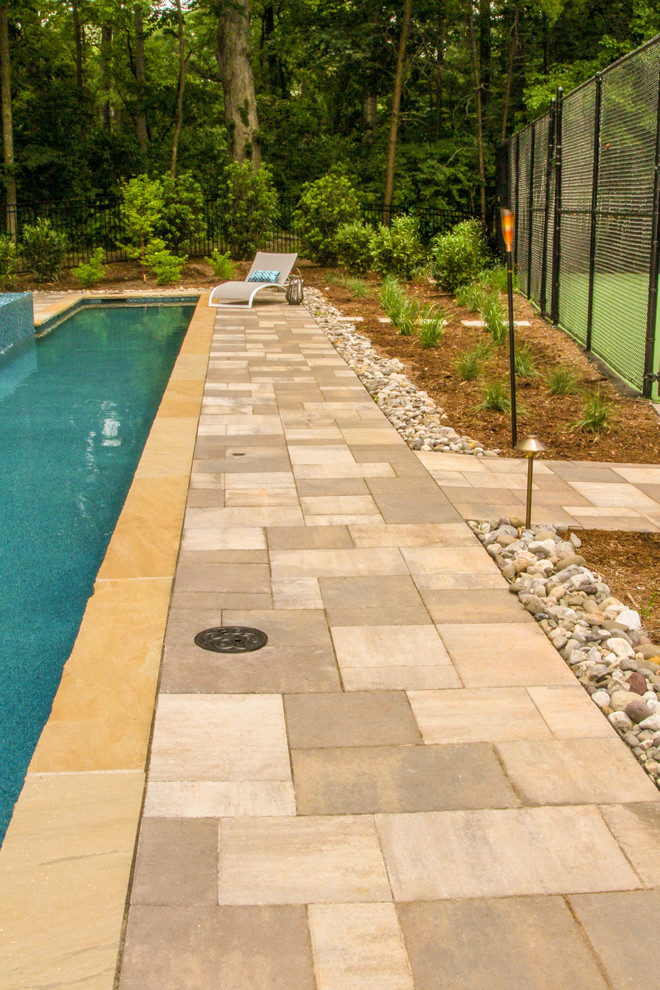 Photo of a large arts and crafts side yard rectangular lap pool in Other with a pool house and natural stone pavers.