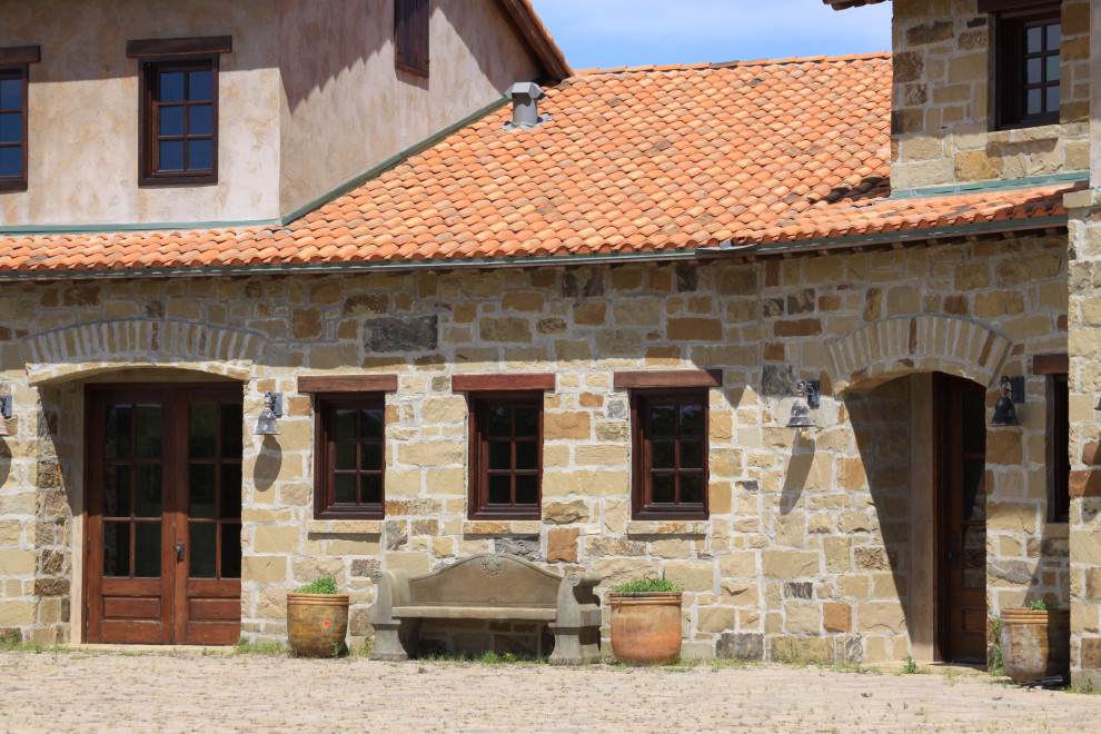 Diseño de fachada de casa roja mediterránea grande de dos plantas con revestimiento de piedra, tejado a dos aguas y tejado de teja de barro