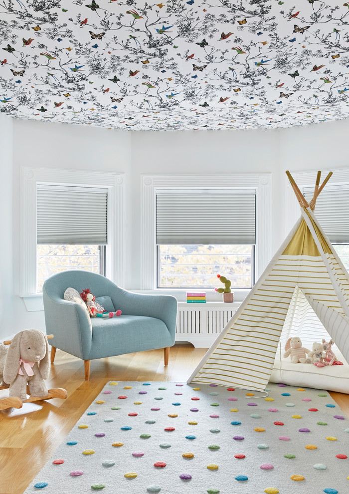 Photo of a large transitional kids' room for girls in New York with white walls, light hardwood floors and brown floor.
