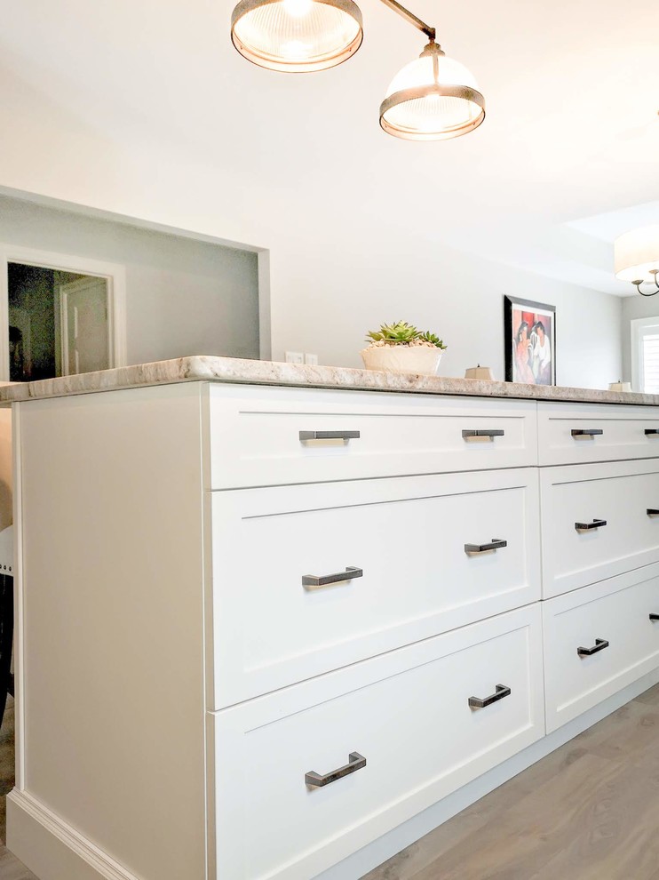Open concept kitchen - mid-sized transitional l-shaped medium tone wood floor and brown floor open concept kitchen idea in Toronto with an undermount sink, shaker cabinets, light wood cabinets, granite countertops, white backsplash, porcelain backsplash, stainless steel appliances, an island and beige countertops