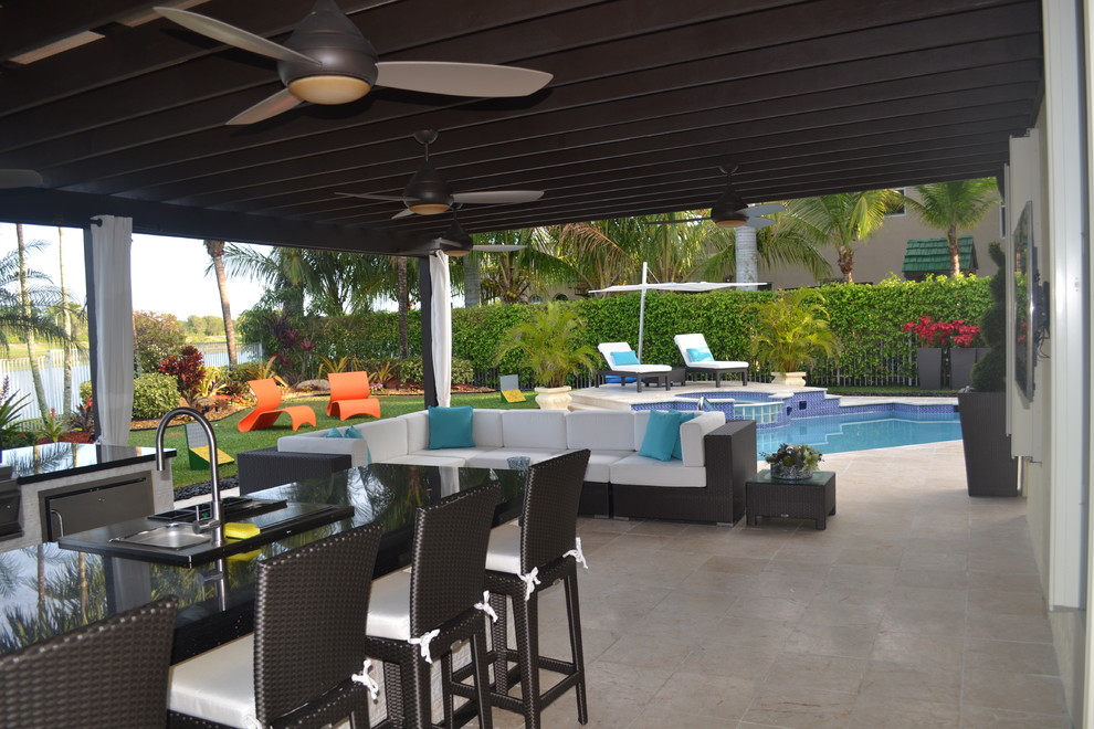 Photo of an expansive contemporary backyard patio in Miami with an outdoor kitchen, natural stone pavers and a pergola.