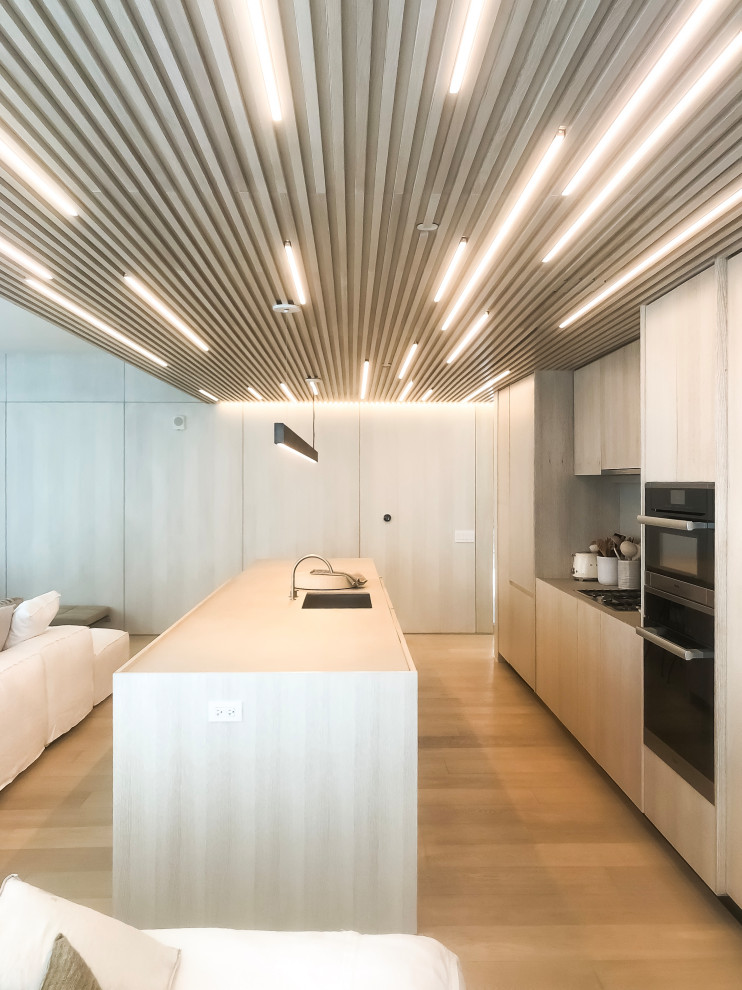 Design ideas for a mid-sized contemporary galley open plan kitchen in Miami with an undermount sink, flat-panel cabinets, beige cabinets, panelled appliances, light hardwood floors, with island, beige floor and beige benchtop.