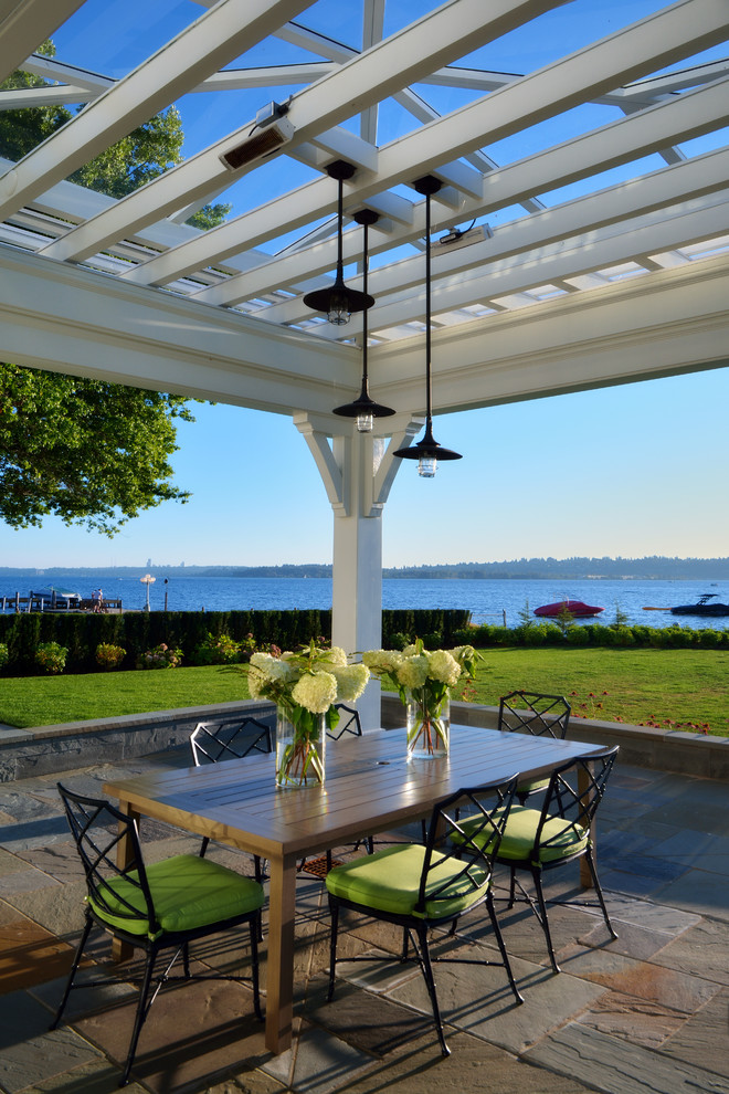Example of a large classic backyard stone patio design in Seattle with a pergola