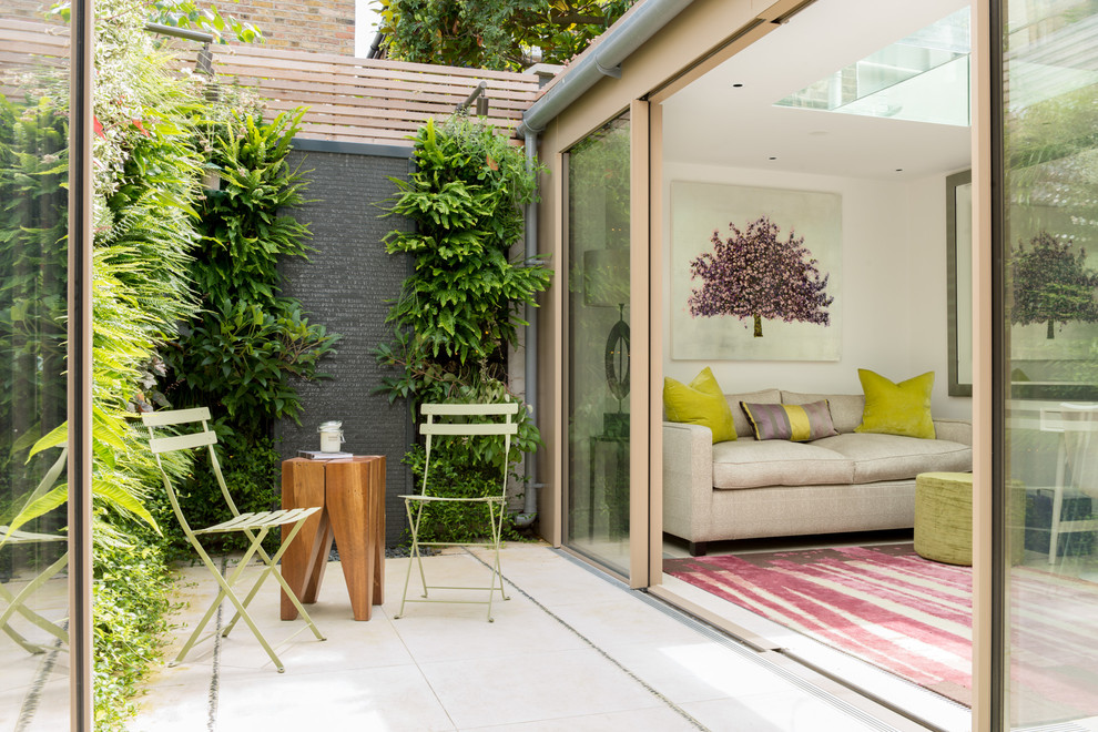 This is an example of a small contemporary backyard patio in London with a vertical garden and no cover.
