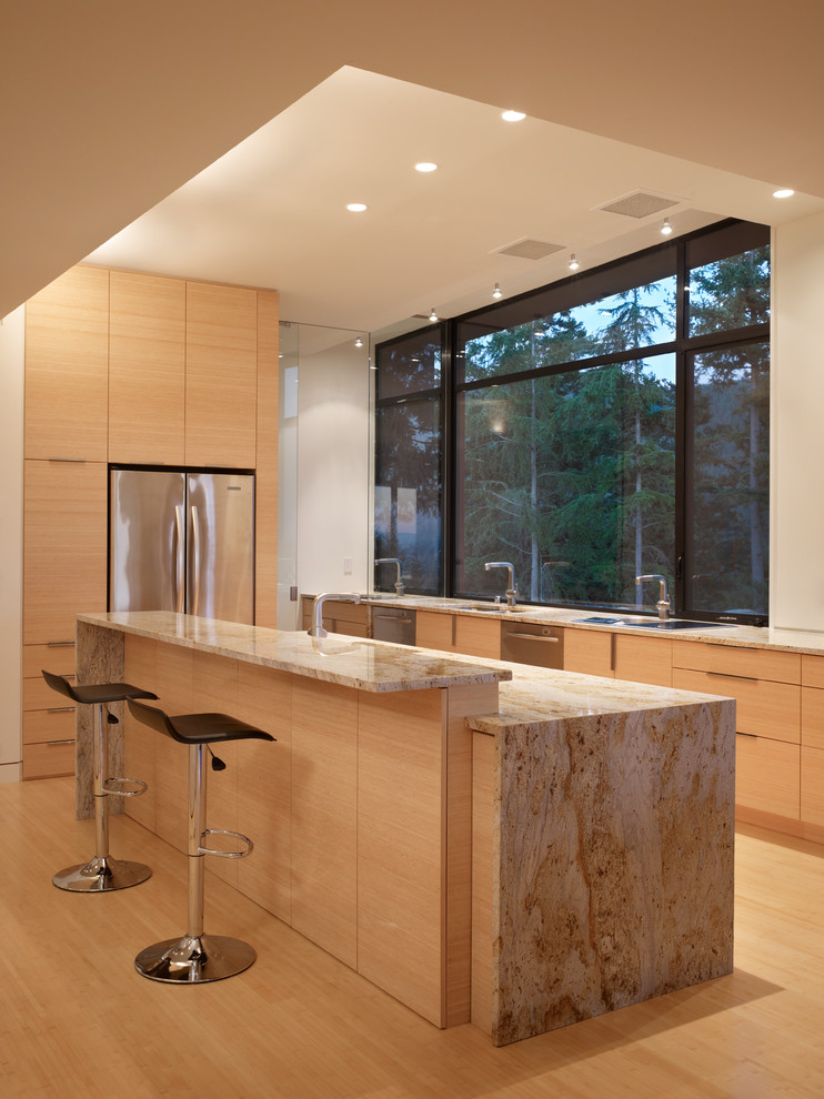 Design ideas for a mid-sized modern single-wall open plan kitchen in Seattle with an undermount sink, flat-panel cabinets, light wood cabinets, granite benchtops, stainless steel appliances, bamboo floors and with island.