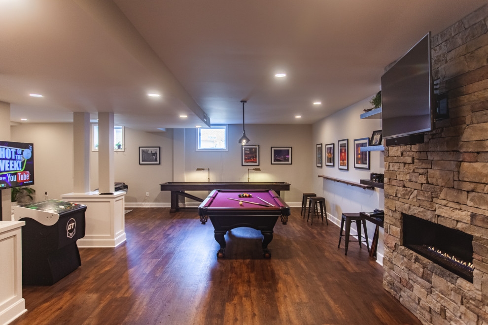 Expansive traditional look-out basement in Cincinnati with a home cinema, grey walls, dark hardwood flooring, a ribbon fireplace, a stone fireplace surround, brown floors and a vaulted ceiling.