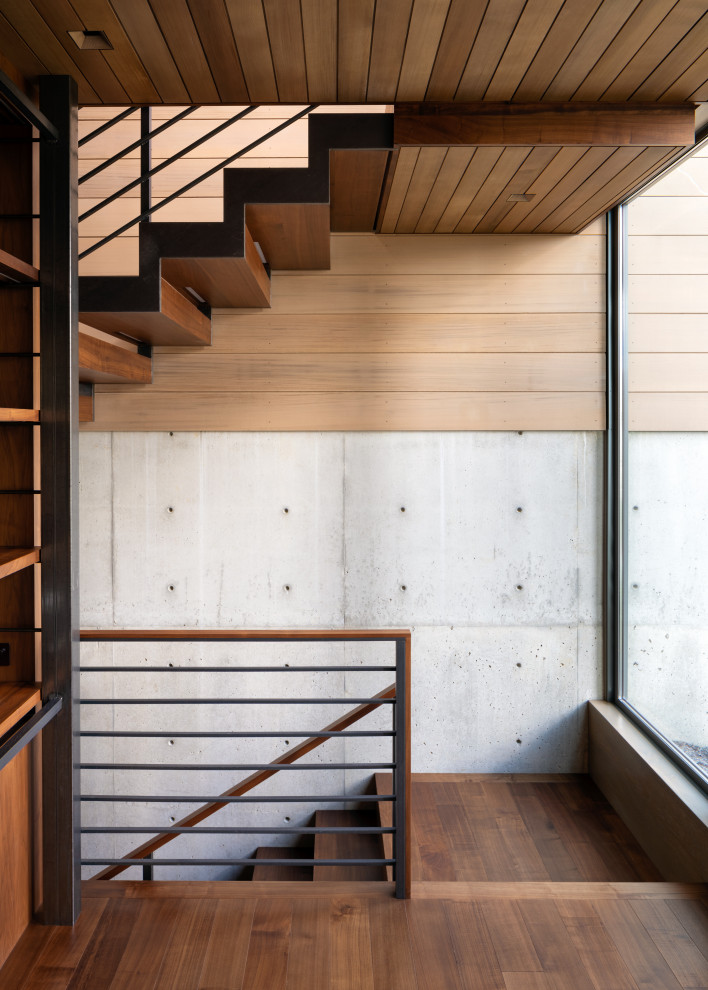 Cette image montre un escalier minimaliste en bois avec des marches en bois et un garde-corps en câble.