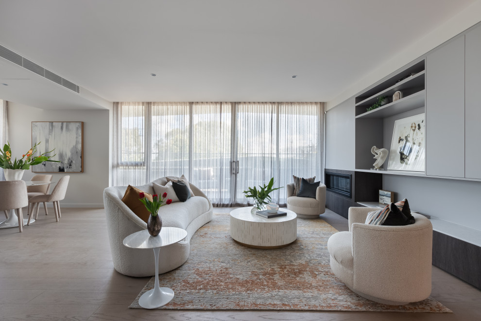 This is an example of a contemporary open concept living room in Melbourne with white walls, light hardwood floors, a ribbon fireplace and beige floor.