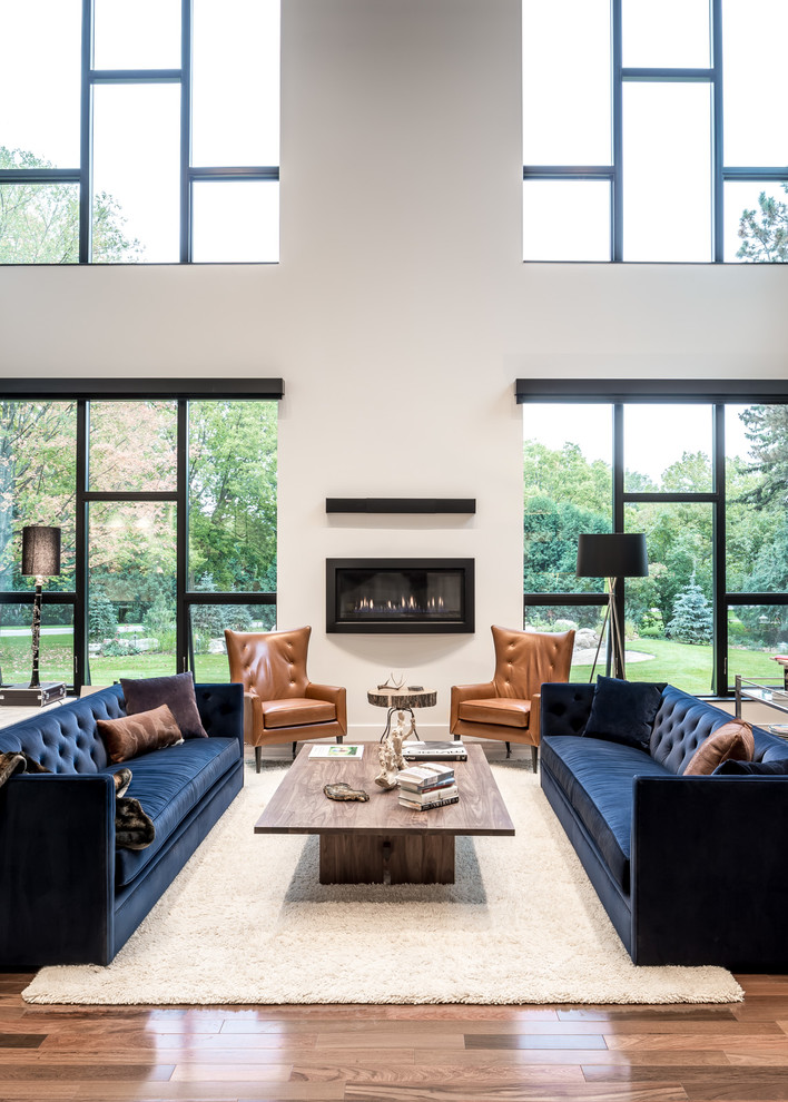 Design ideas for a large contemporary open concept family room in Minneapolis with white walls, medium hardwood floors, a ribbon fireplace, a plaster fireplace surround, no tv and beige floor.