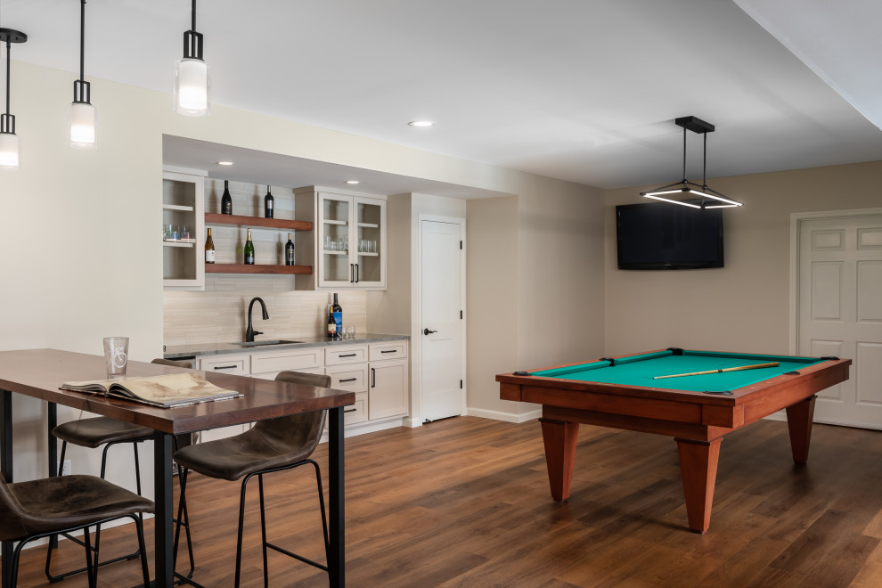 Example of a large minimalist walk-out basement game room design in St Louis with beige walls, a standard fireplace and a stacked stone fireplace