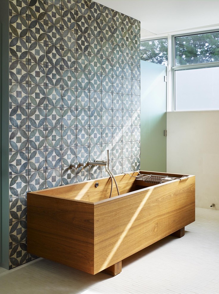 This is an example of a mid-sized contemporary master bathroom in Toronto with a freestanding tub, blue tile, stone tile, blue walls and mosaic tile floors.