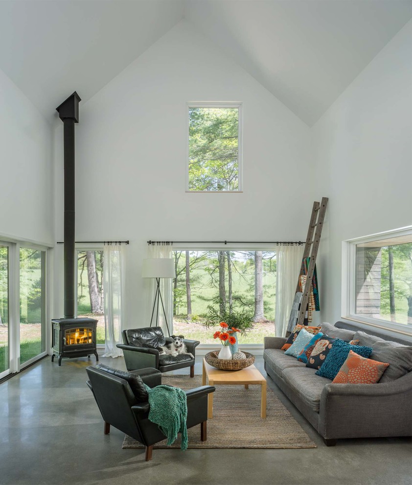 This is an example of a mid-sized contemporary formal open concept living room in Burlington with white walls, concrete floors, a wood stove, no tv and grey floor.