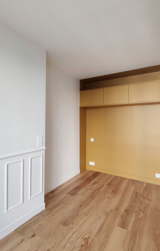 Foto de dormitorio principal y beige y blanco minimalista de tamaño medio con paredes amarillas, suelo de madera clara, suelo marrón y boiserie