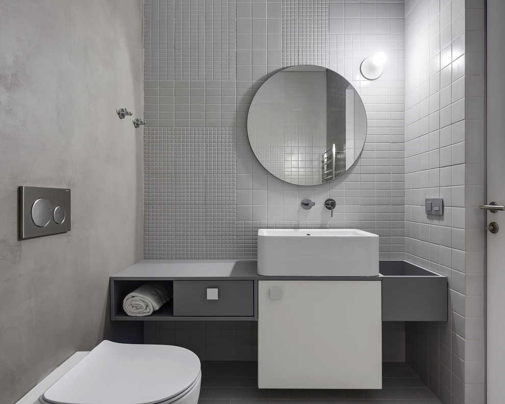 Contemporary powder room in Other with flat-panel cabinets, a bidet, gray tile, grey walls and a vessel sink.