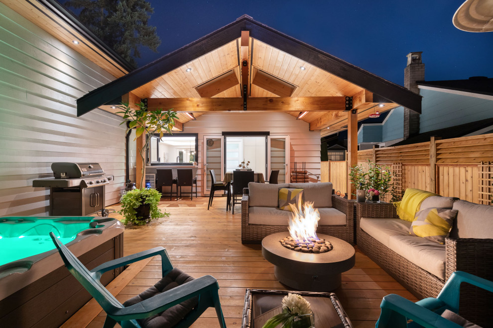 Inspiration for a mid-sized transitional backyard and ground level deck in Vancouver with a fire feature, a roof extension and wood railing.