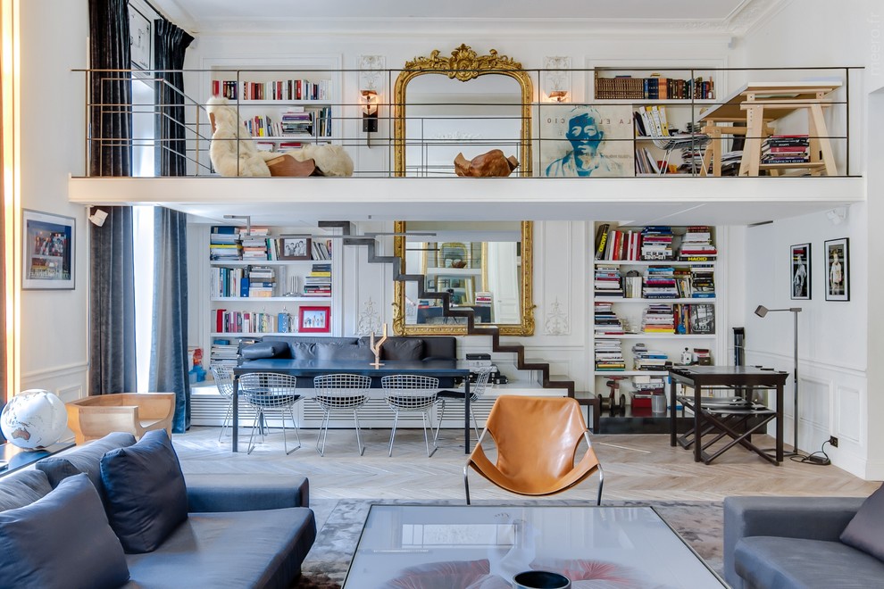 Mid-sized eclectic open concept living room in Paris with a library, white walls, light hardwood floors, no fireplace and no tv.
