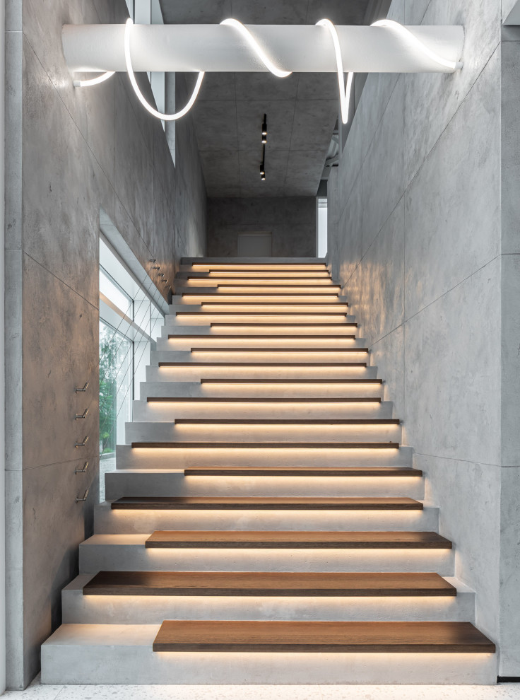Réalisation d'un escalier droit design avec des marches en bois, des contremarches en béton et un garde-corps en câble.