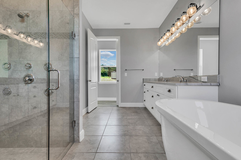 This is an example of a large country master bathroom in Orlando with shaker cabinets, white cabinets, a freestanding tub, an open shower, a one-piece toilet, gray tile, mirror tile, grey walls, porcelain floors, an undermount sink, engineered quartz benchtops, grey floor, an open shower and grey benchtops.