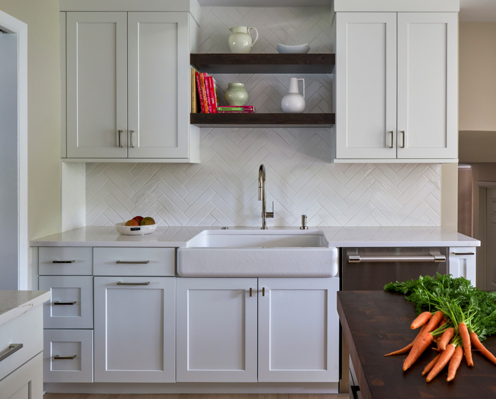 Large transitional u-shaped light wood floor, brown floor and coffered ceiling eat-in kitchen photo in Chicago with a farmhouse sink, shaker cabinets, white cabinets, quartz countertops, white backsplash, subway tile backsplash, stainless steel appliances, an island and multicolored countertops