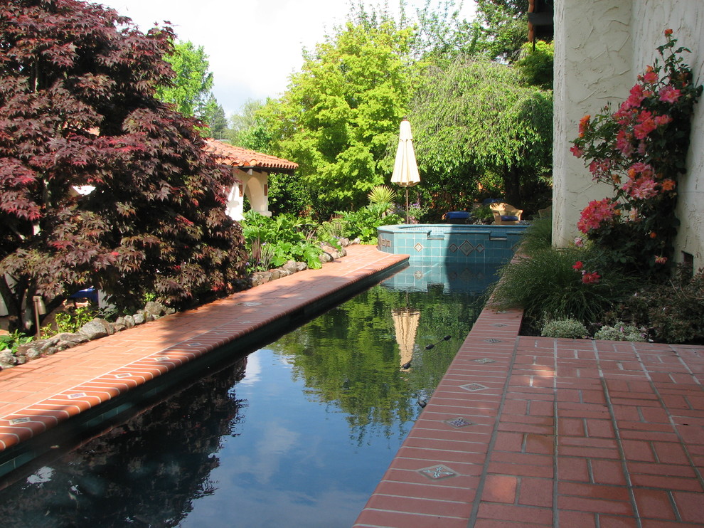 This is an example of a mid-sized mediterranean side yard rectangular lap pool in San Francisco with a hot tub and brick pavers.