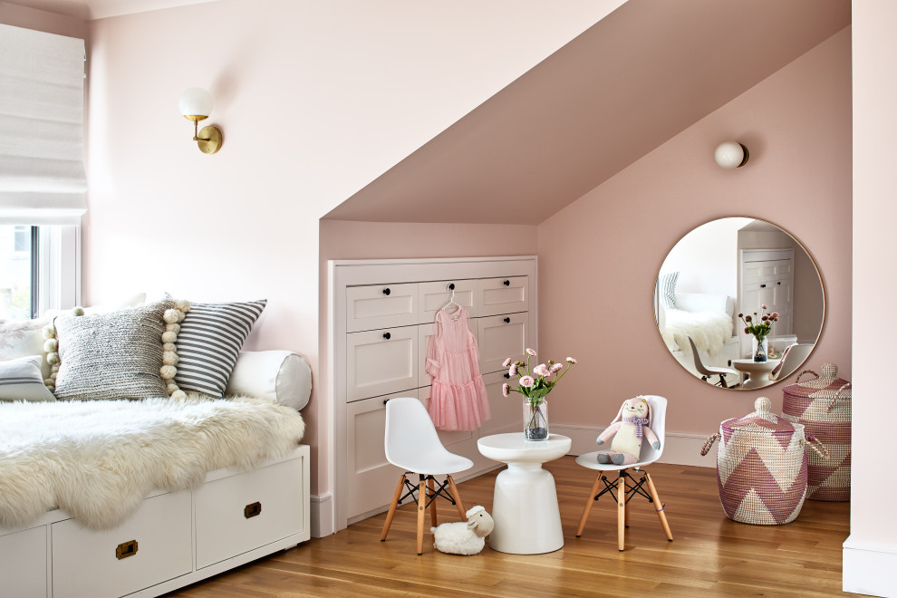 Inspiration for a large transitional kids' room for girls in Los Angeles with pink walls, medium hardwood floors and brown floor.
