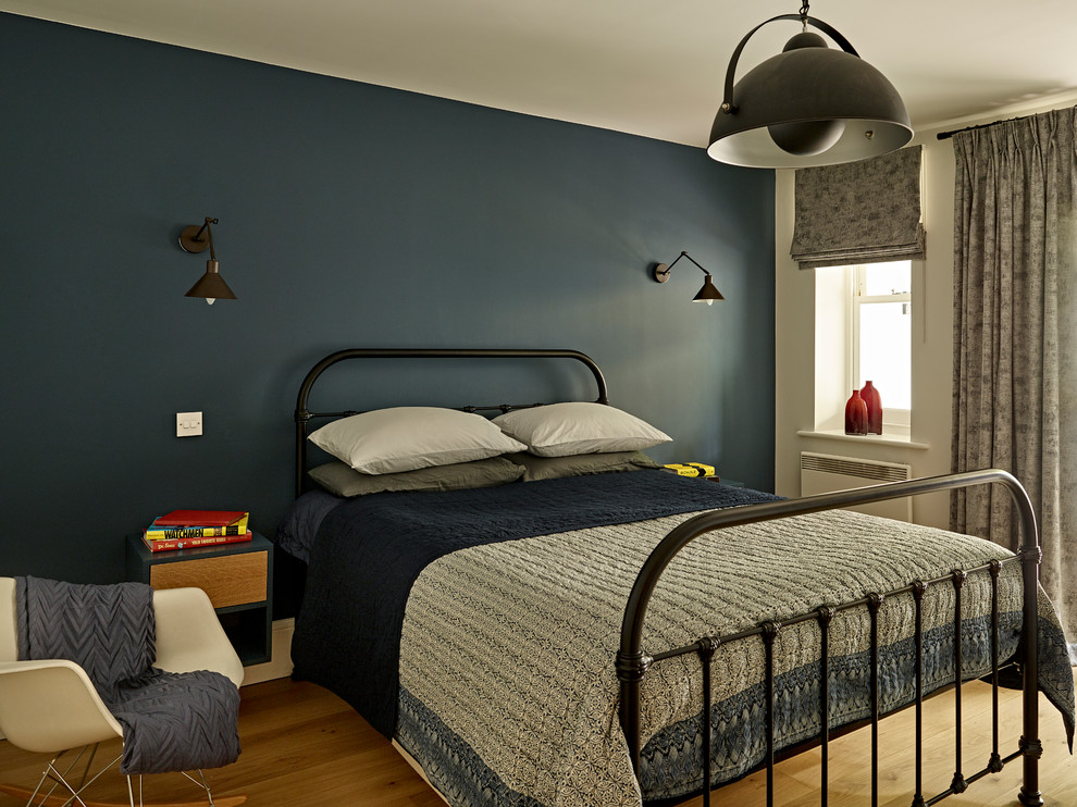 This is an example of a mid-sized contemporary kids' room for boys in London with blue walls, light hardwood floors and beige floor.