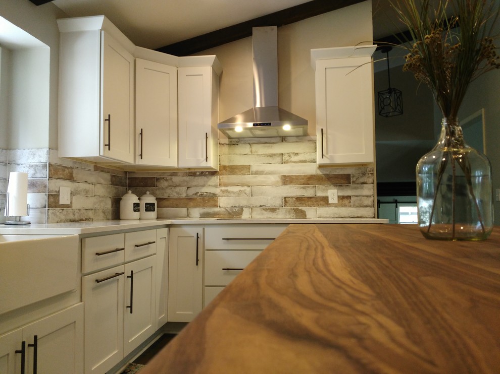 Inspiration for a mid-sized transitional l-shaped dark wood floor and brown floor eat-in kitchen remodel with a farmhouse sink, shaker cabinets, white cabinets, wood countertops, gray backsplash, marble backsplash, stainless steel appliances and an island