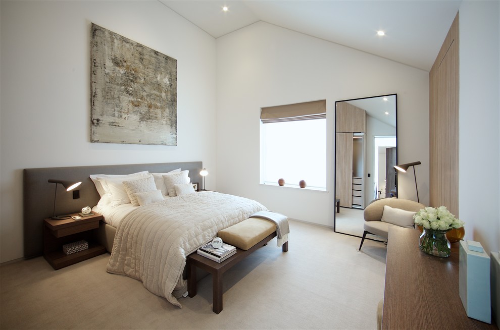 This is an example of an expansive contemporary bedroom in London with white walls, carpet and beige floor.
