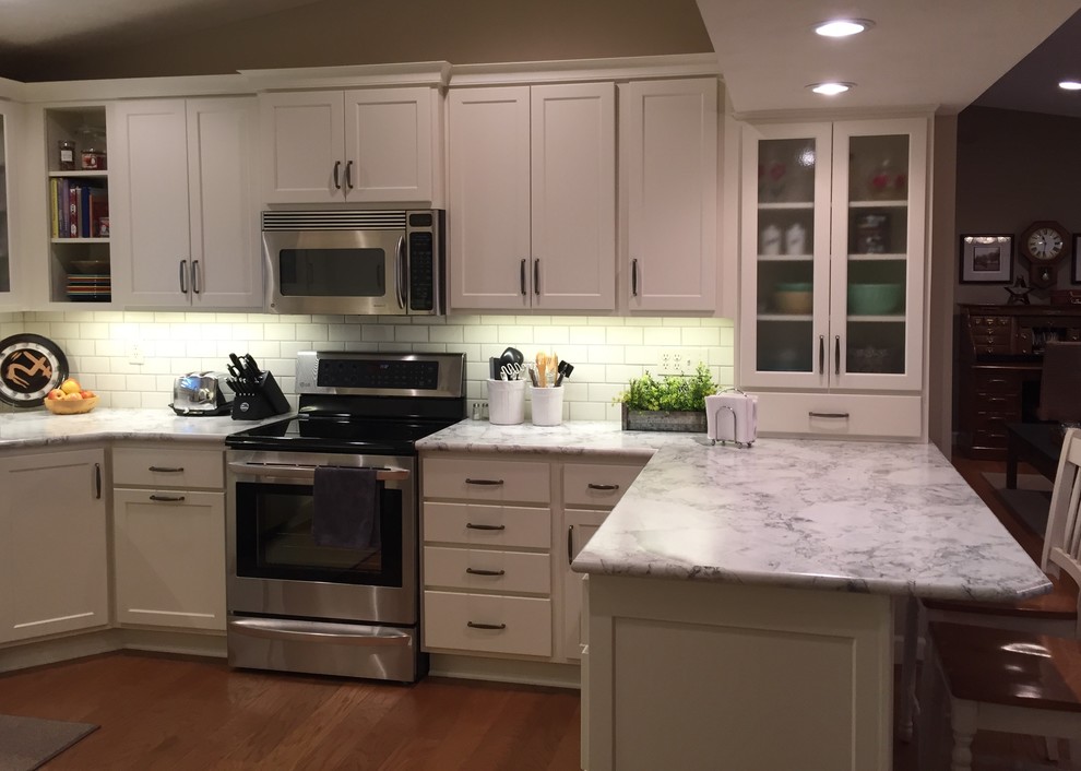 Eat-in kitchen - mid-sized transitional u-shaped medium tone wood floor eat-in kitchen idea with an integrated sink, shaker cabinets, white cabinets, laminate countertops, white backsplash, subway tile backsplash, stainless steel appliances and a peninsula