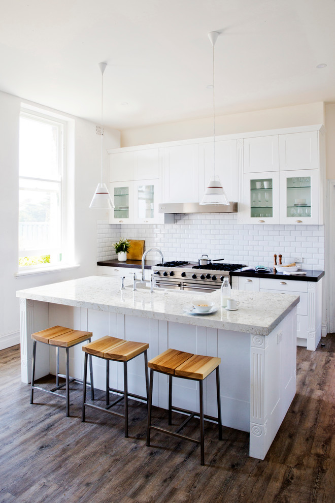 Design ideas for a small modern kitchen in Baltimore with a drop-in sink, flat-panel cabinets, white cabinets, quartzite benchtops, white splashback, glass tile splashback, stainless steel appliances, dark hardwood floors and with island.
