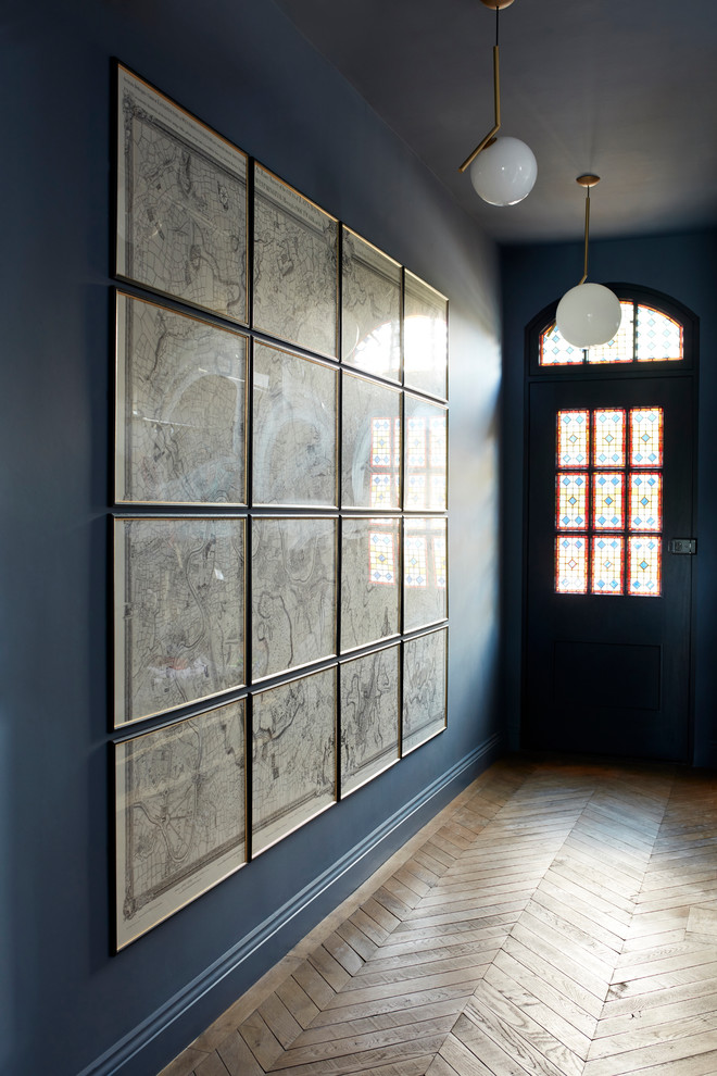 Design ideas for a mid-sized traditional foyer in London with blue walls and medium hardwood floors.