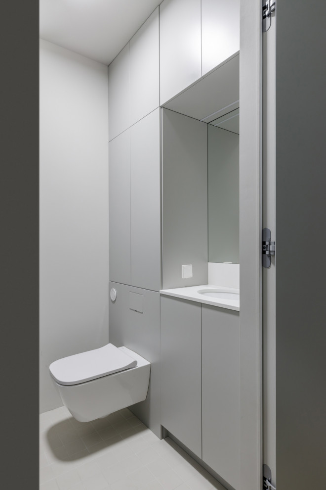 Exemple d'un petit WC et toilettes tendance avec un placard à porte plane, des portes de placard grises, un mur blanc, un sol en carrelage de porcelaine, un plan de toilette en quartz modifié, un sol blanc, un plan de toilette blanc et meuble-lavabo encastré.