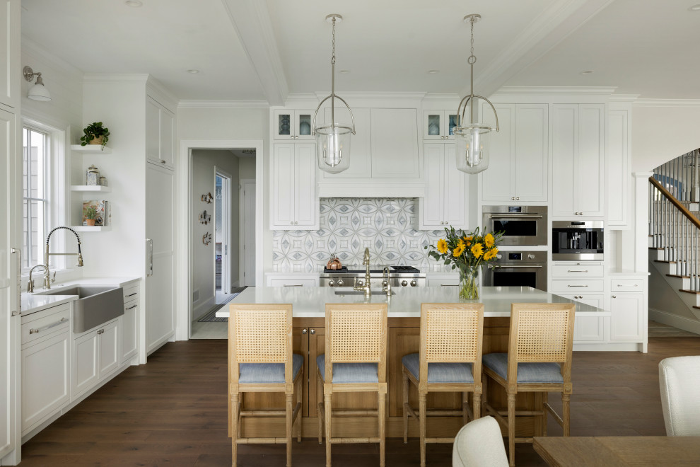 Klassische Küche in L-Form mit Landhausspüle, Schrankfronten im Shaker-Stil, weißen Schränken, Küchengeräten aus Edelstahl, dunklem Holzboden, Kücheninsel, braunem Boden und weißer Arbeitsplatte in Minneapolis