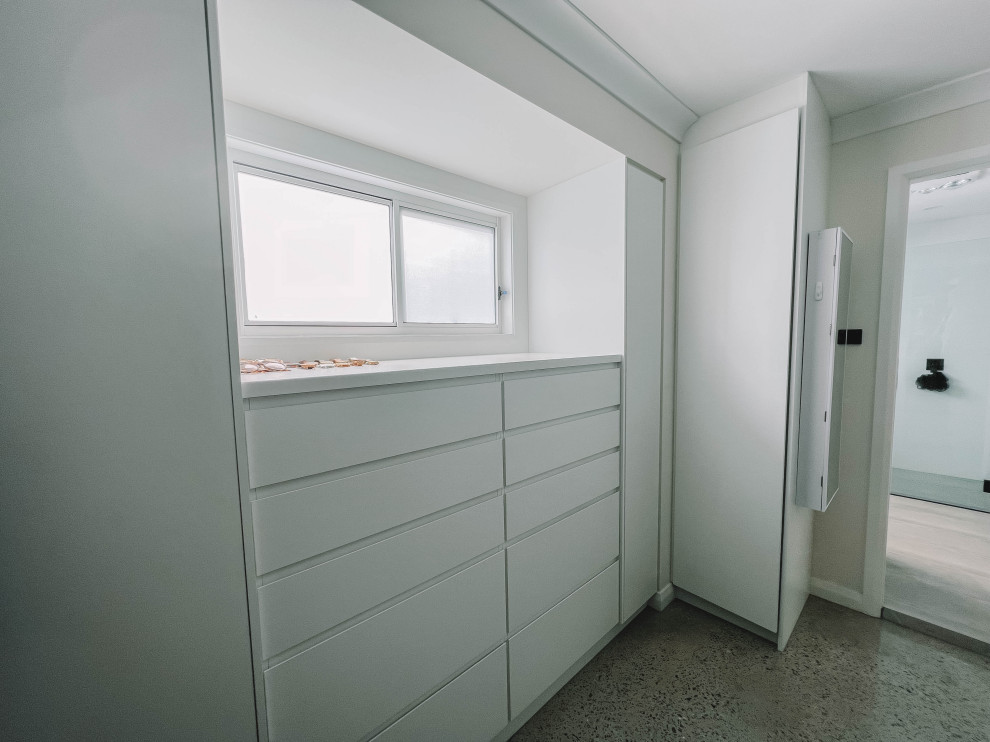 Mid-sized scandinavian gender-neutral walk-in wardrobe in Sydney with flat-panel cabinets, white cabinets, concrete floors, grey floor and wood.
