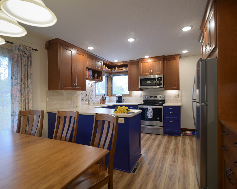 Small eclectic u-shaped eat-in kitchen in Minneapolis with an undermount sink, shaker cabinets, blue cabinets, laminate benchtops, beige splashback, travertine splashback, stainless steel appliances, laminate floors, brown floor and beige benchtop.