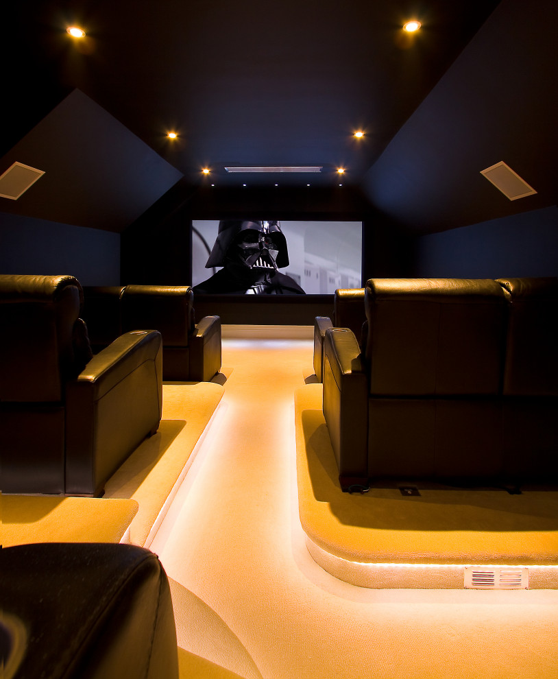 Photo of a mid-sized modern enclosed home theatre in Kent with black walls, carpet, a projector screen and beige floor.