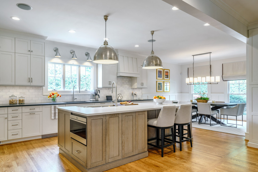 Eat-in kitchen - large transitional galley medium tone wood floor and brown floor eat-in kitchen idea with an undermount sink, shaker cabinets, white cabinets, quartz countertops, white backsplash, marble backsplash, stainless steel appliances, an island and white countertops