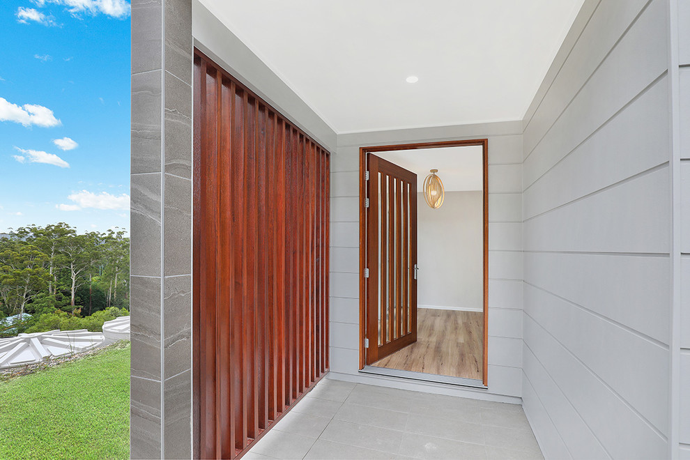 Inspiration for a mid-sized beach style front door in Sunshine Coast with grey walls, concrete floors, a pivot front door, a dark wood front door and grey floor.