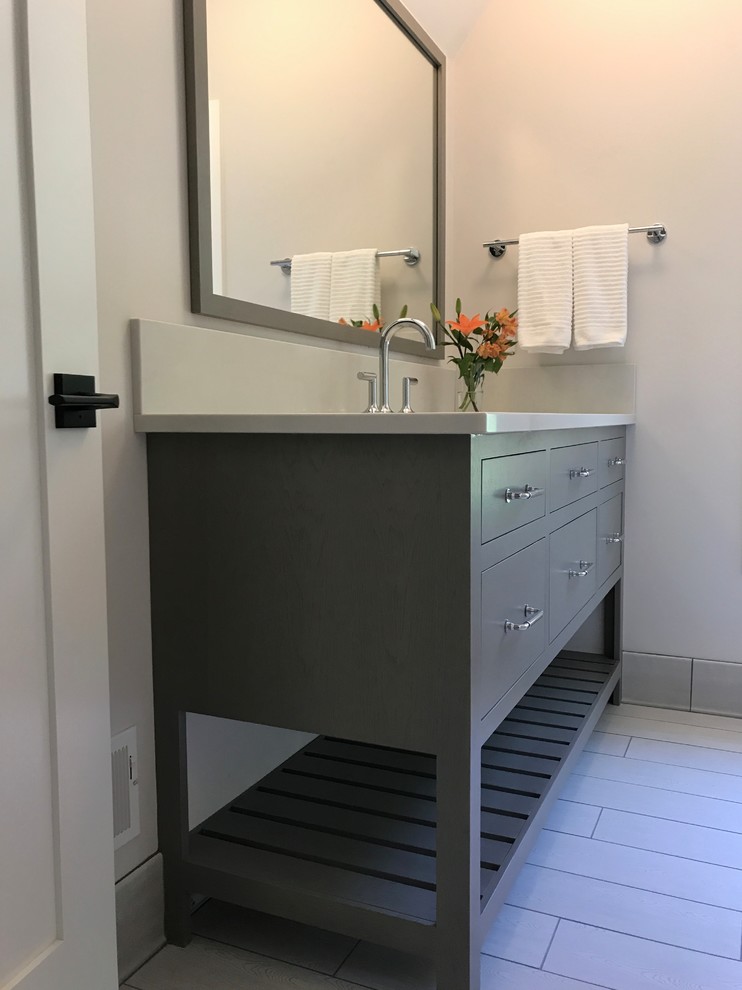 This is an example of a mid-sized country kids bathroom with flat-panel cabinets, grey cabinets, an alcove tub, a two-piece toilet, ceramic tile, grey walls, porcelain floors, an undermount sink, engineered quartz benchtops, white floor, a shower curtain and white tile.