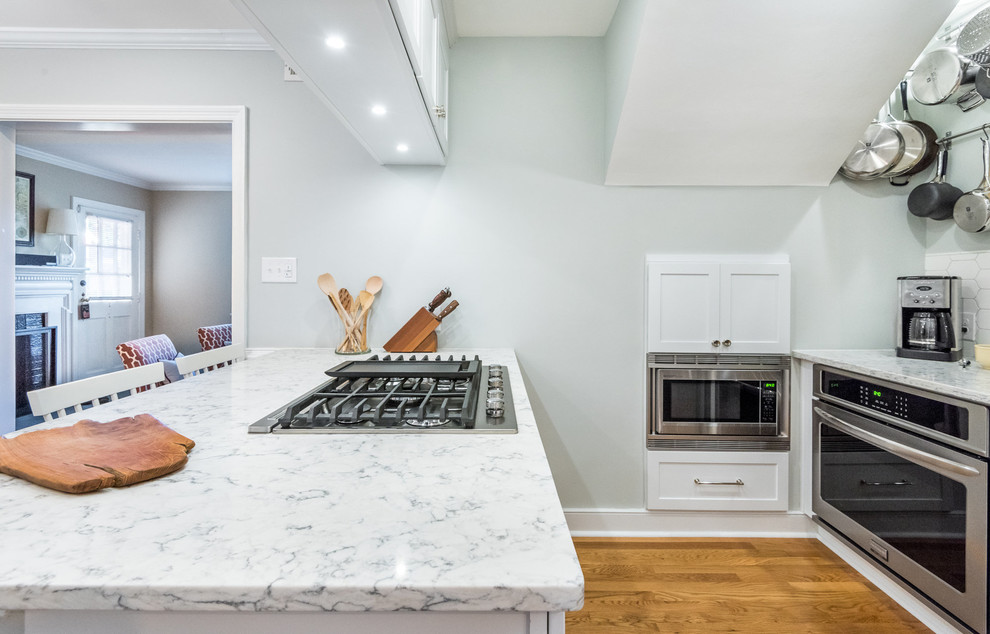 Inspiration for a transitional medium tone wood floor kitchen remodel in Richmond with a single-bowl sink, shaker cabinets, white cabinets, quartzite countertops, white backsplash, mosaic tile backsplash, stainless steel appliances and a peninsula