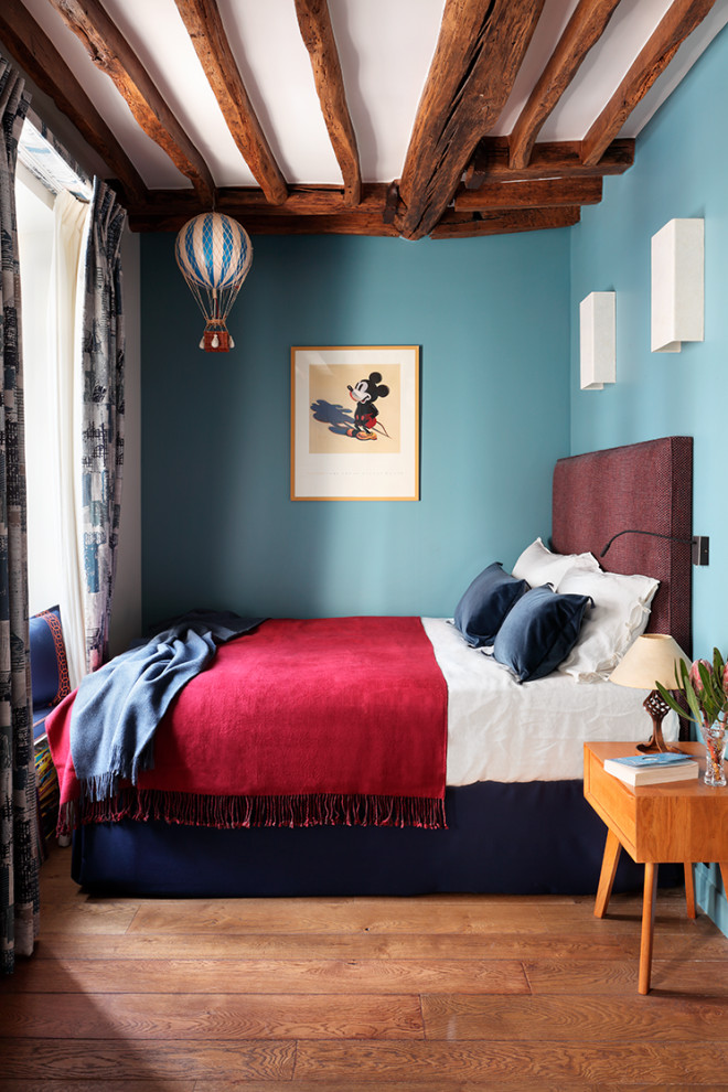 Inspiration for an eclectic bedroom in London with blue walls, medium hardwood floors and brown floor.