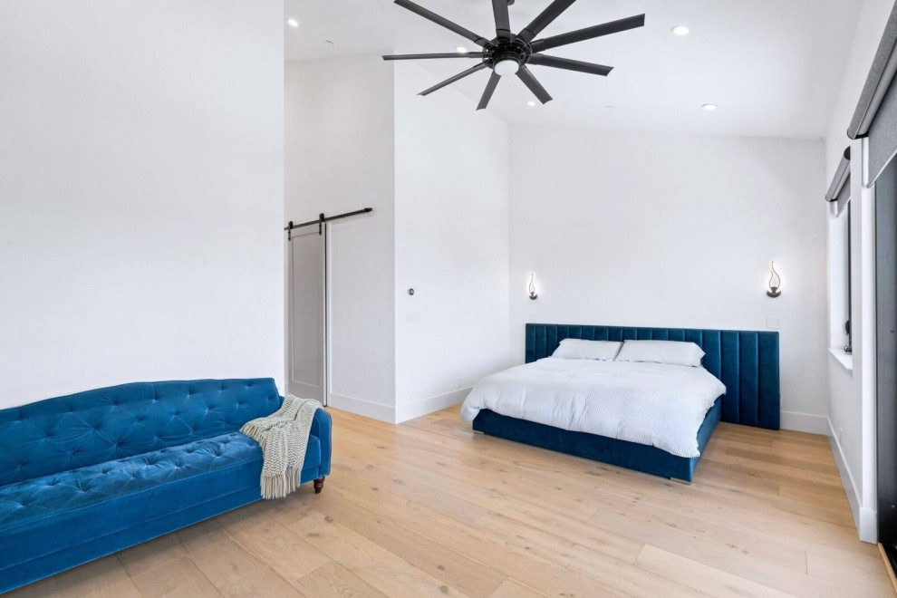 Vaulted Primary Bedroom with Blue Upholstered Bed and Wood Flooring
