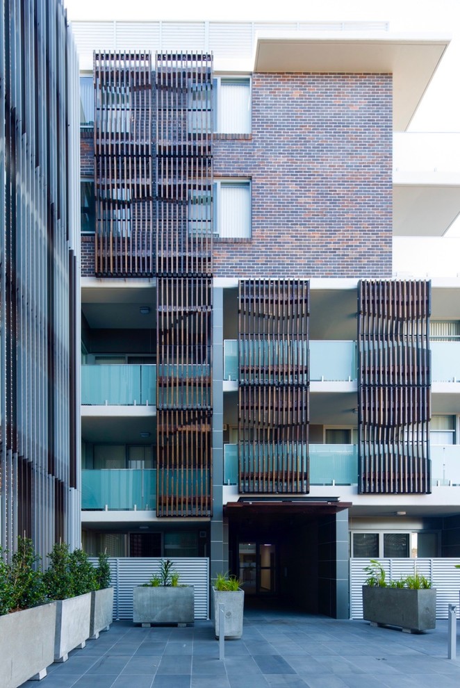 Photo of an expansive industrial three-storey apartment exterior in Sydney with wood siding.
