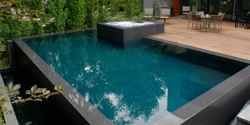 Example of a large minimalist backyard rectangular infinity hot tub design