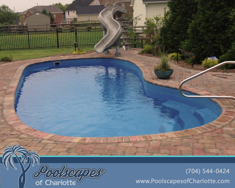 Inspiration for a mid-sized traditional backyard l-shaped pool in Charlotte with natural stone pavers.